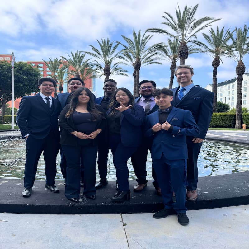 Legends Ascend Inc sales team members in professional business attire standing by a fountain with palm trees in Santa Rosa California